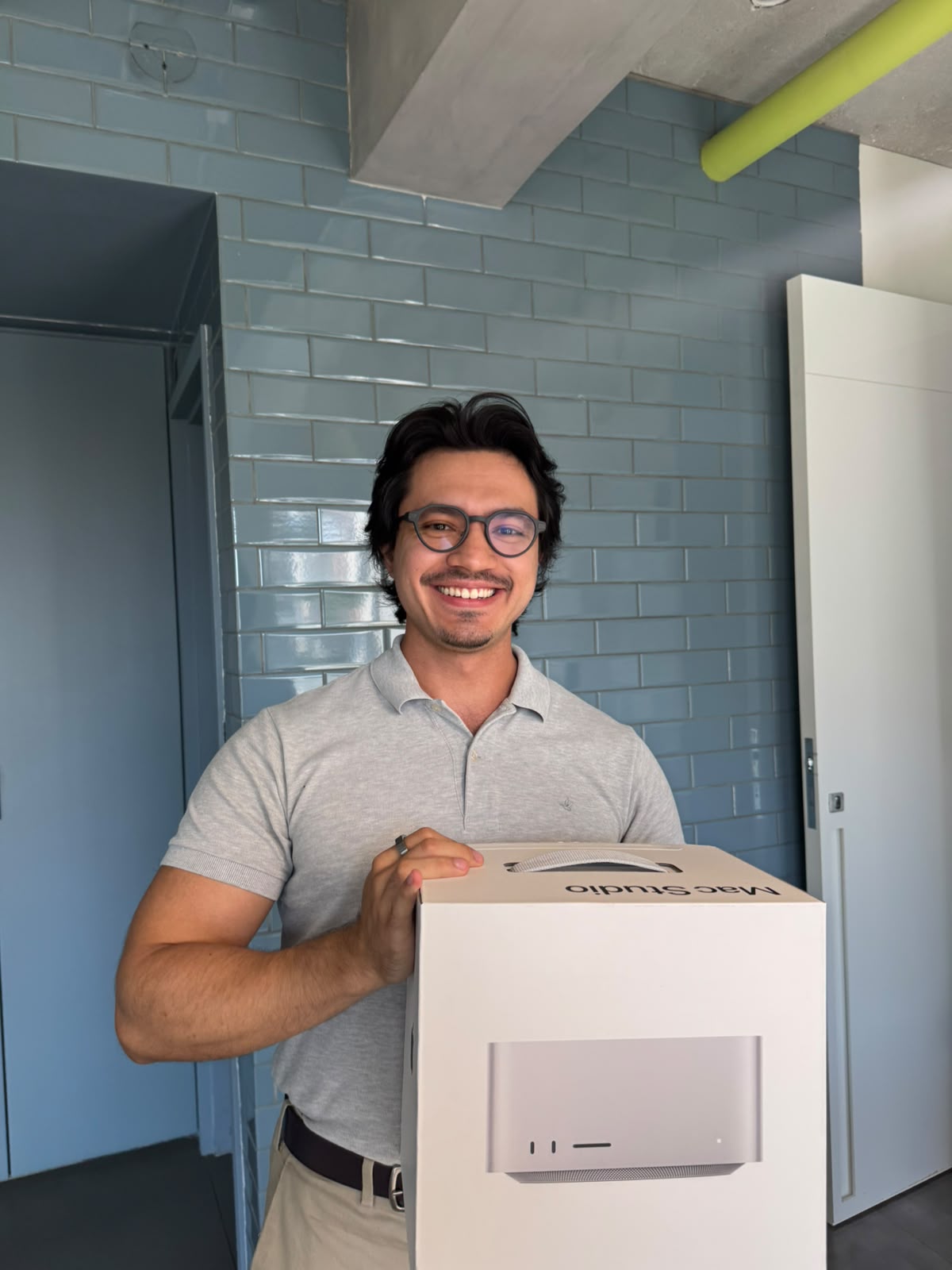 Pessoa sorrindo segurando a caixa do Mac Studio